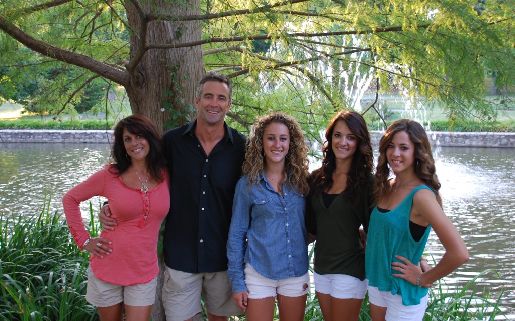 Dr. Olson with his wife and 3 daughters in front of a pond with fountain